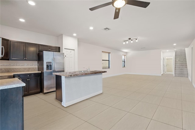 kitchen featuring an island with sink, sink, light tile patterned floors, ceiling fan, and stainless steel refrigerator with ice dispenser