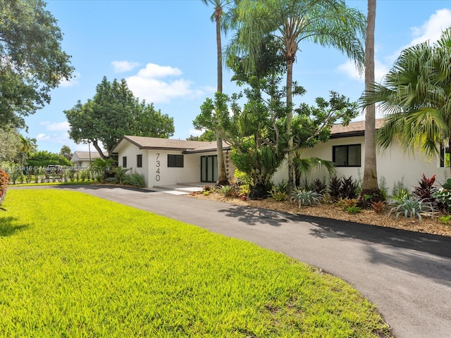 view of front of house featuring stucco siding, a front lawn, and driveway