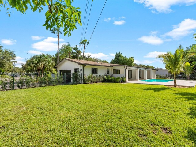 rear view of property featuring a fenced in pool and a lawn