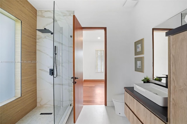 bathroom featuring a tile shower, vanity, and toilet