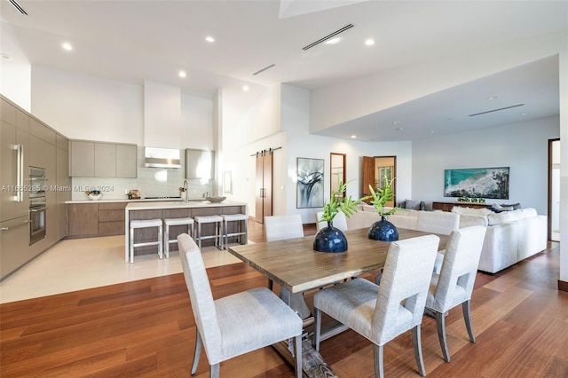 dining area with hardwood / wood-style floors, a towering ceiling, and sink