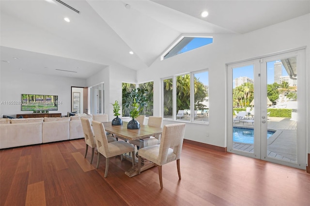 dining space with hardwood / wood-style flooring, high vaulted ceiling, and french doors