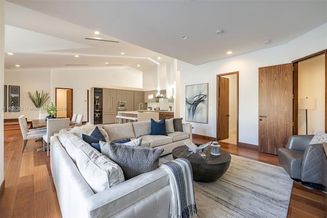 living room with light hardwood / wood-style floors, lofted ceiling, and sink