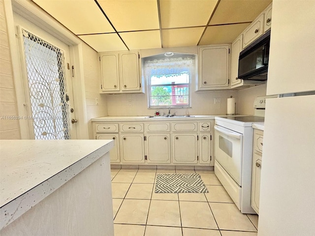 kitchen featuring a paneled ceiling, white appliances, light tile patterned floors, and sink