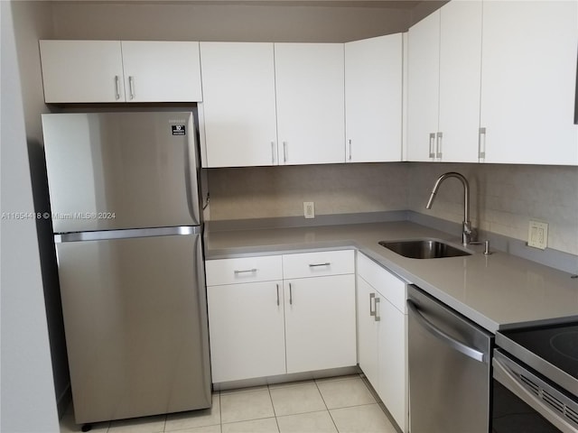 kitchen with tasteful backsplash, stainless steel appliances, sink, white cabinets, and light tile patterned flooring