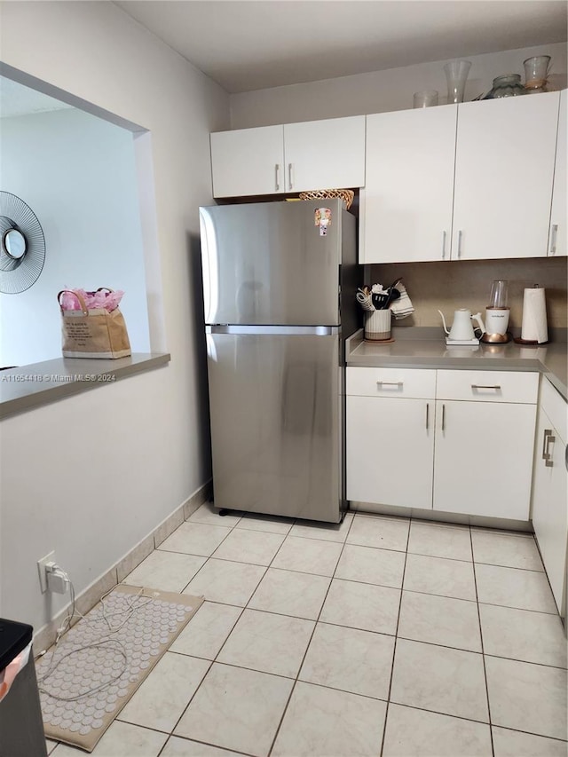 kitchen with white cabinetry, stainless steel counters, stainless steel refrigerator, and light tile patterned flooring