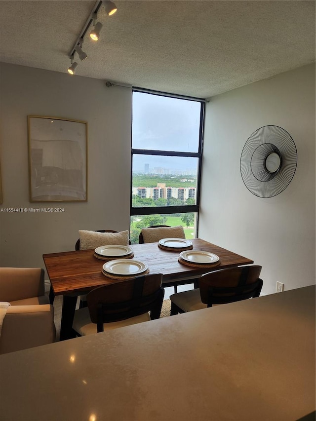 dining area with a textured ceiling and rail lighting