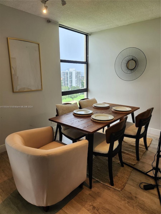 dining room featuring a textured ceiling, expansive windows, and hardwood / wood-style floors