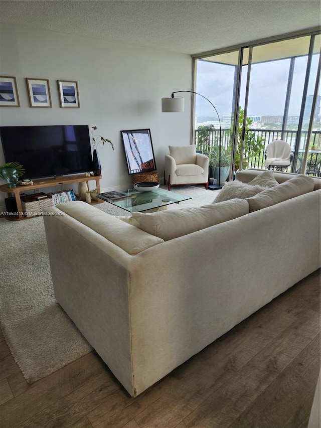 living room featuring a textured ceiling, hardwood / wood-style floors, and a wall of windows