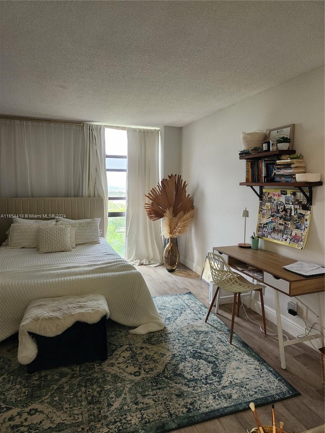 bedroom with a textured ceiling and wood-type flooring