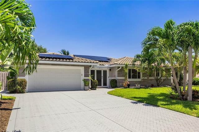 view of front of house featuring a front yard, solar panels, and a garage