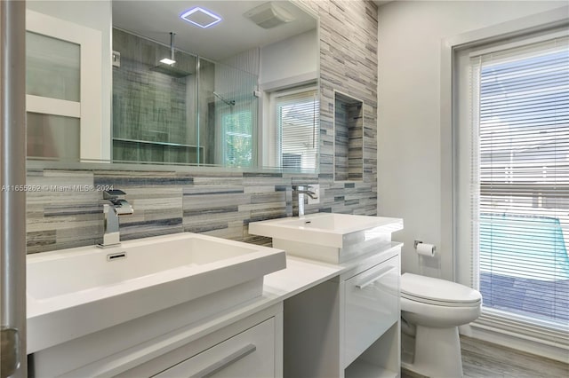 bathroom featuring tasteful backsplash, hardwood / wood-style floors, toilet, a shower with door, and vanity