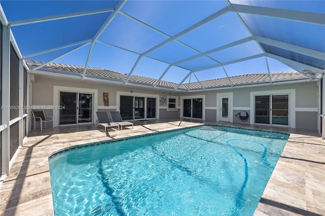 view of pool with glass enclosure and a patio