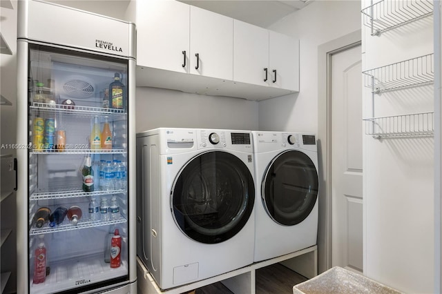 clothes washing area with washer and dryer and cabinets