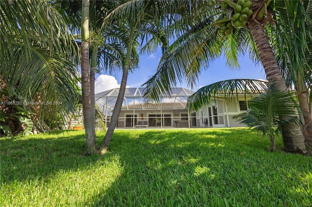 rear view of house featuring glass enclosure and a lawn