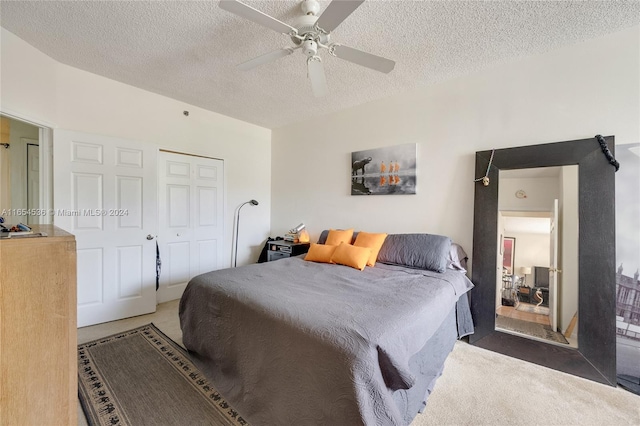 bedroom featuring a textured ceiling, dark carpet, ceiling fan, and a closet