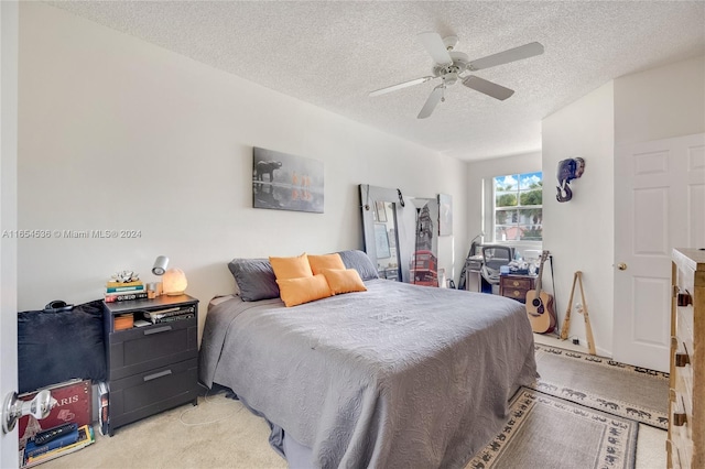 bedroom featuring a textured ceiling, ceiling fan, and light carpet