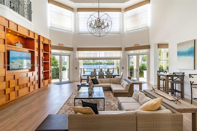 living room with a towering ceiling, hardwood / wood-style flooring, an inviting chandelier, and french doors