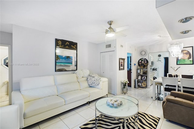 tiled living room with ceiling fan with notable chandelier