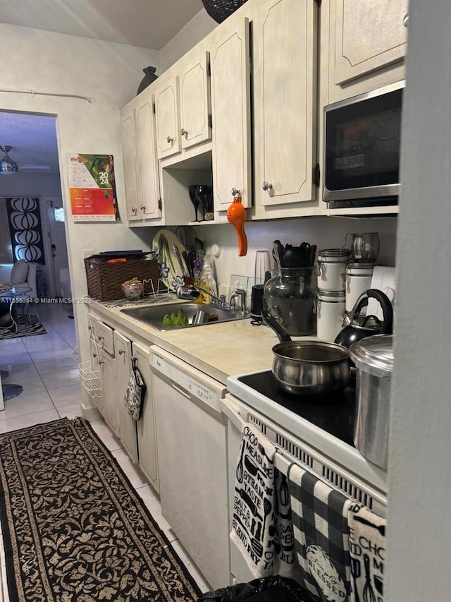 kitchen with white dishwasher, light tile patterned floors, and sink