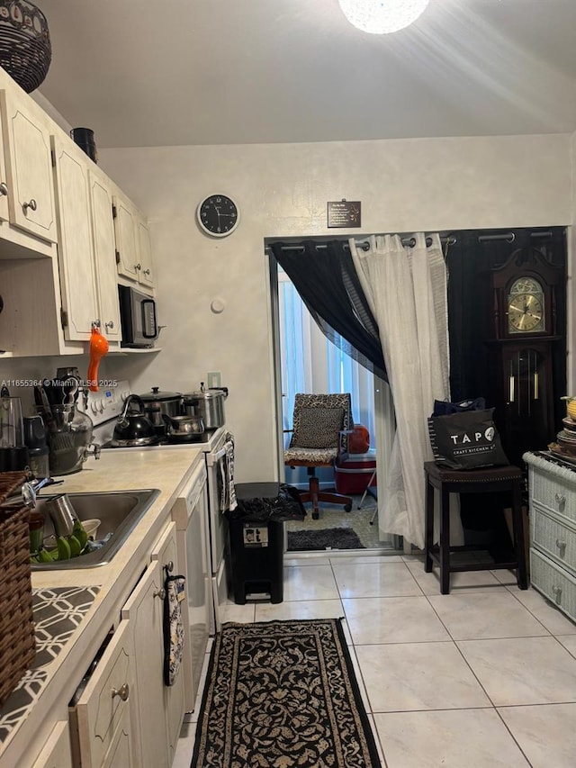 kitchen with light tile patterned floors, electric range, and sink