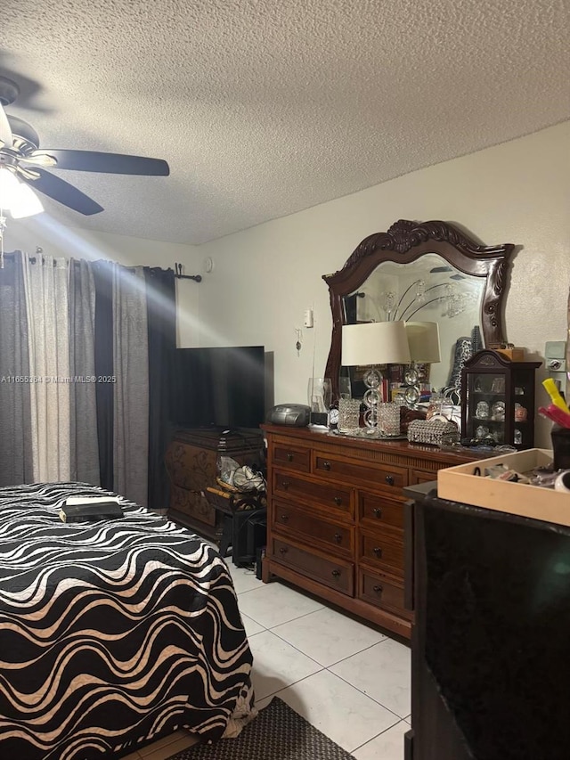 bedroom with ceiling fan, light tile patterned flooring, and a textured ceiling