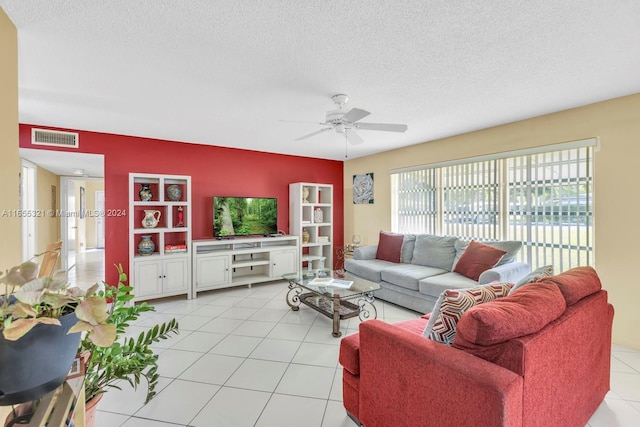 living room with ceiling fan, light tile patterned floors, and a textured ceiling