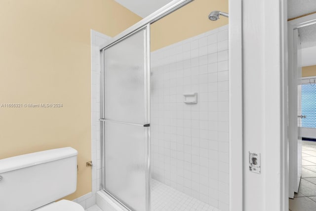 bathroom featuring a shower with door and toilet