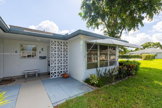 doorway to property with a lawn and a patio area