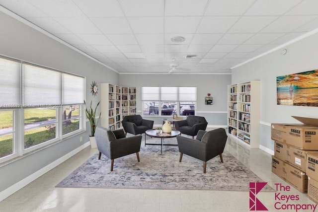 living room with ceiling fan, a paneled ceiling, and ornamental molding