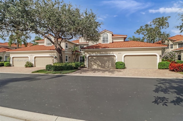 view of front of home featuring a garage, a tiled roof, decorative driveway, and stucco siding