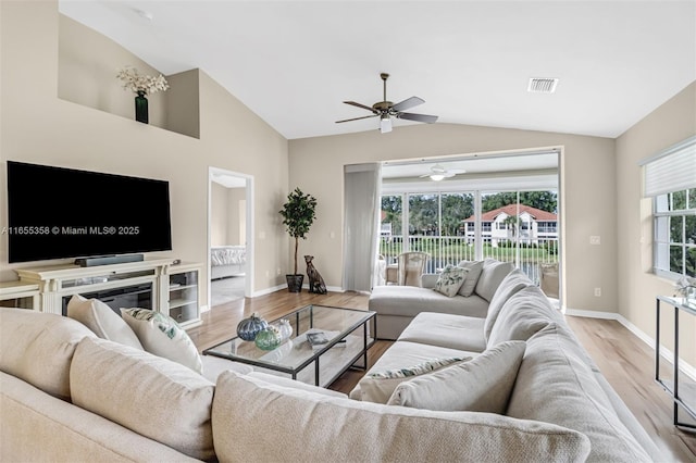 living area with lofted ceiling, visible vents, baseboards, and wood finished floors