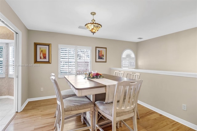 dining space featuring light wood-type flooring, a wealth of natural light, and baseboards