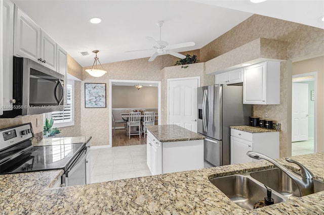 kitchen with vaulted ceiling, stainless steel appliances, a sink, and light stone countertops