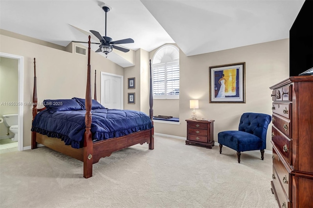 bedroom with ensuite bathroom, light colored carpet, visible vents, baseboards, and vaulted ceiling