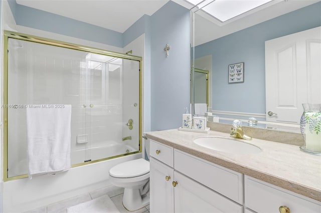 bathroom featuring a skylight, toilet, combined bath / shower with glass door, vanity, and tile patterned floors