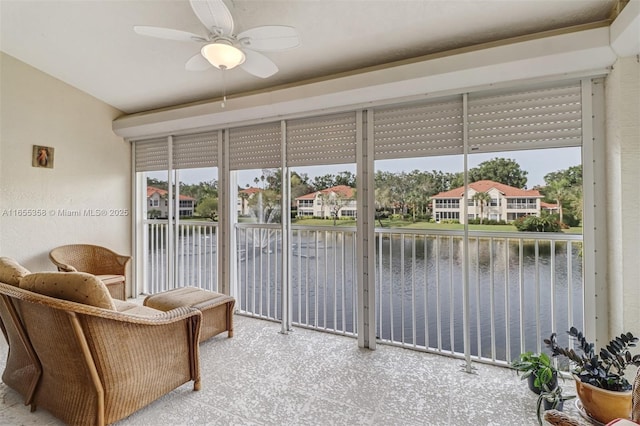 sunroom / solarium featuring a water view, plenty of natural light, and a ceiling fan