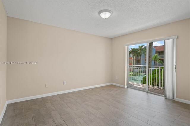 unfurnished room with a textured ceiling and light hardwood / wood-style flooring