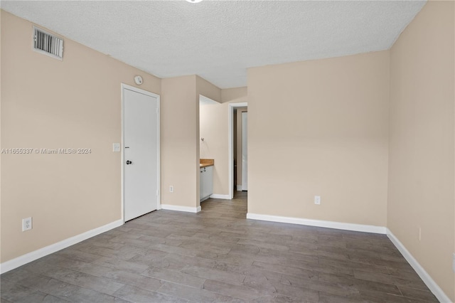 spare room featuring a textured ceiling and hardwood / wood-style floors