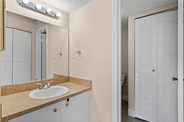 bathroom featuring vanity, toilet, and a textured ceiling