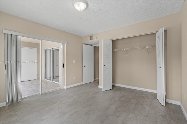 unfurnished bedroom featuring a closet, a textured ceiling, and light hardwood / wood-style flooring