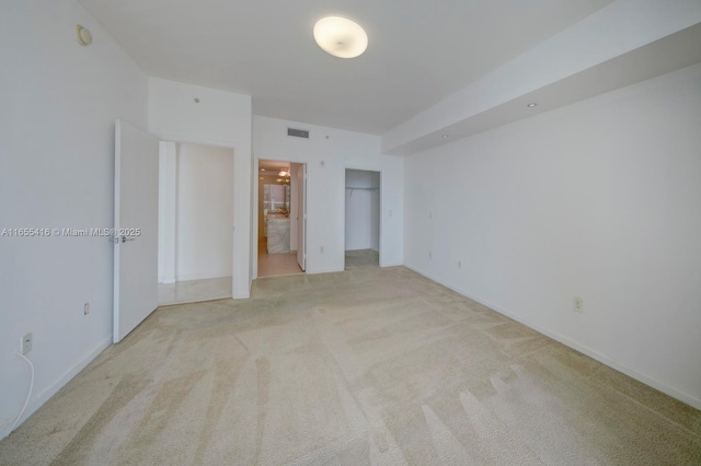 unfurnished bedroom with ensuite bath and light carpet