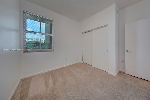 unfurnished bedroom with light colored carpet and a closet