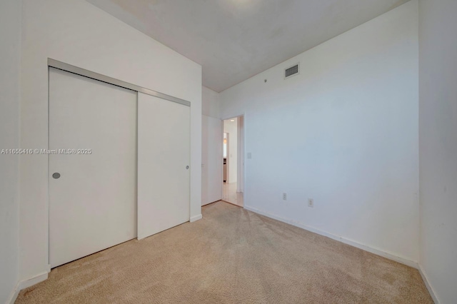 unfurnished bedroom featuring light carpet and a closet