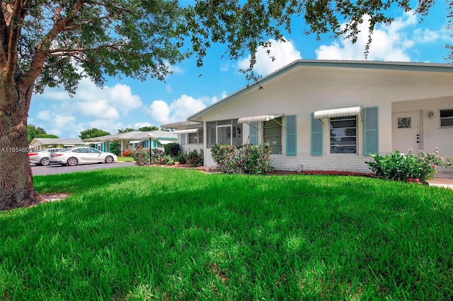 view of front of house with a front lawn, brick siding, and stucco siding