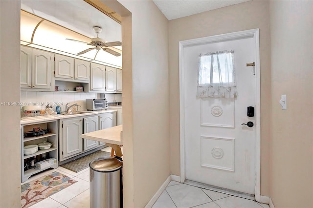 interior space featuring light tile patterned floors, a toaster, baseboards, and a ceiling fan