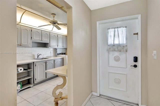 foyer entrance featuring light tile patterned floors, a ceiling fan, baseboards, and washer / dryer
