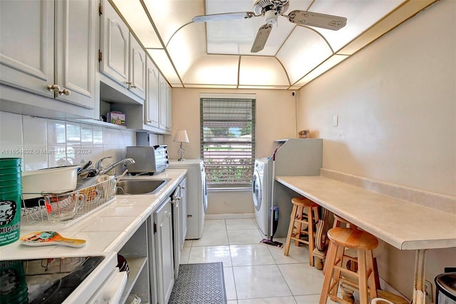 kitchen featuring backsplash, light countertops, light tile patterned floors, a ceiling fan, and a sink