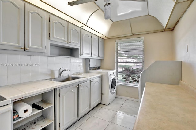 laundry area featuring cabinet space, light tile patterned floors, baseboards, and washing machine and clothes dryer