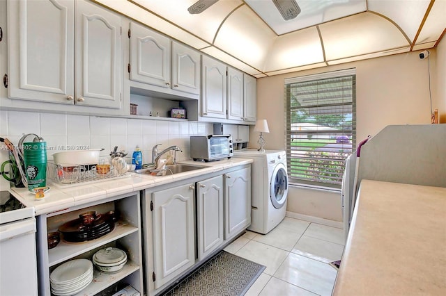 washroom featuring light tile patterned floors, baseboards, washer / dryer, a toaster, and a sink